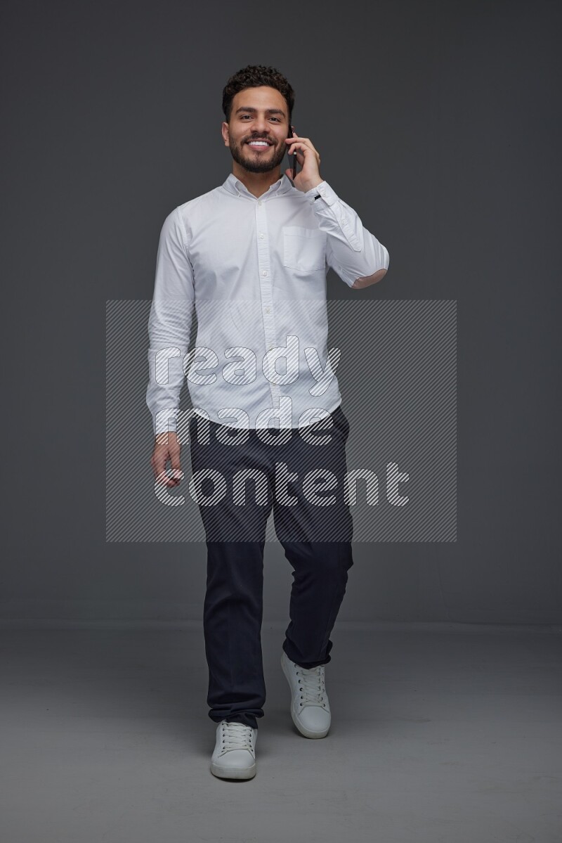 A man wearing smart casual talking in the phone eye level on a gray background