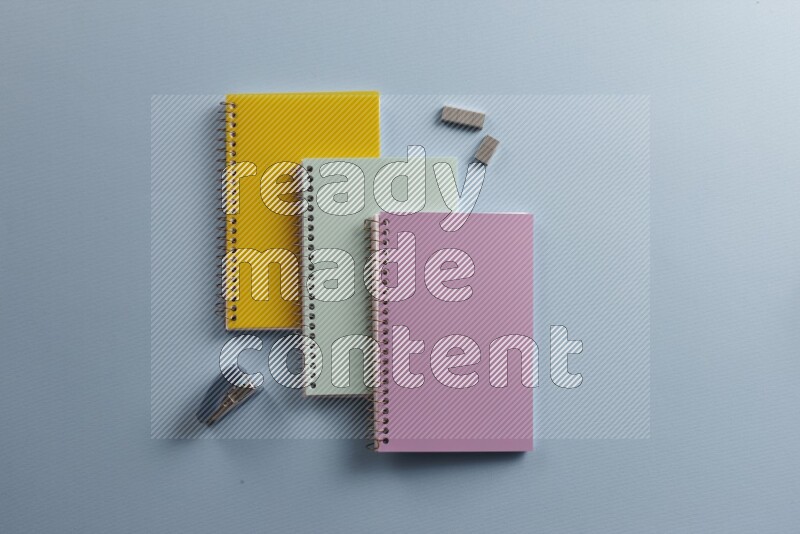 Multicolored notebooks with different school supplies on blue background