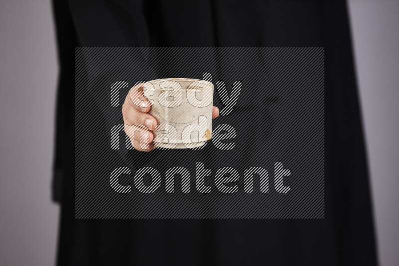 A woman in black abaya holding different pottery essentials in different positions