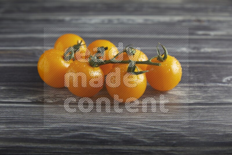 Yellow cherry tomato vein on a textured grey wooden background 45 degree