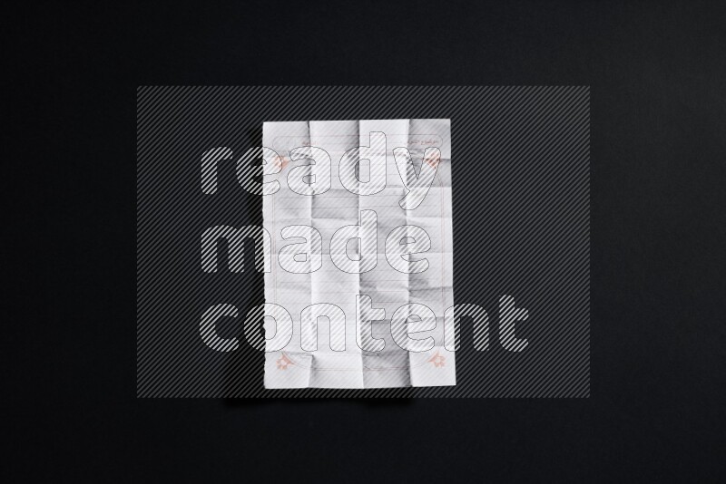 Folded notebook sheet on black background