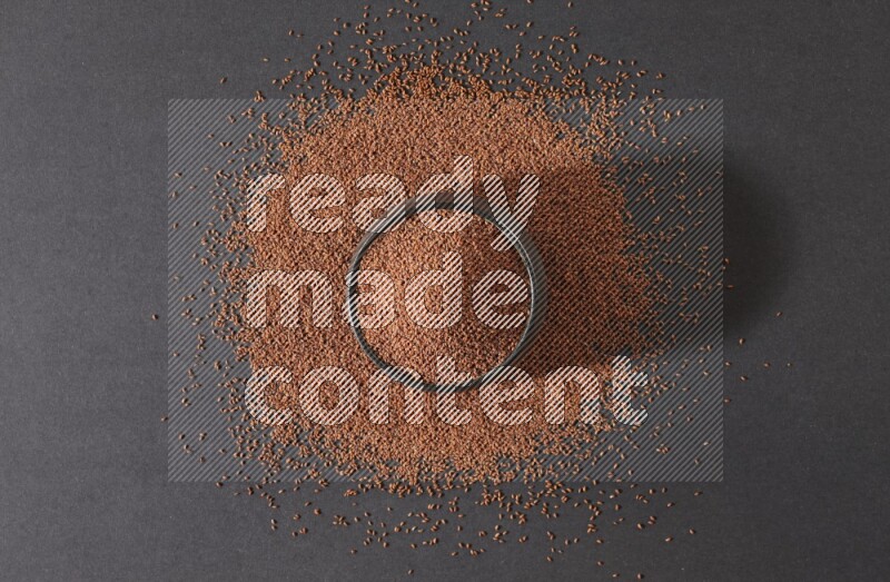 وعاء فخاري أسود ممتلئ ببذور حب الرشاد محاط بالبذور على أرضية سوداء