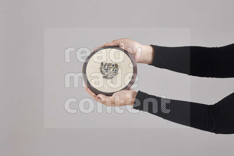 A woman in black abaya holding different pottery essentials in different positions