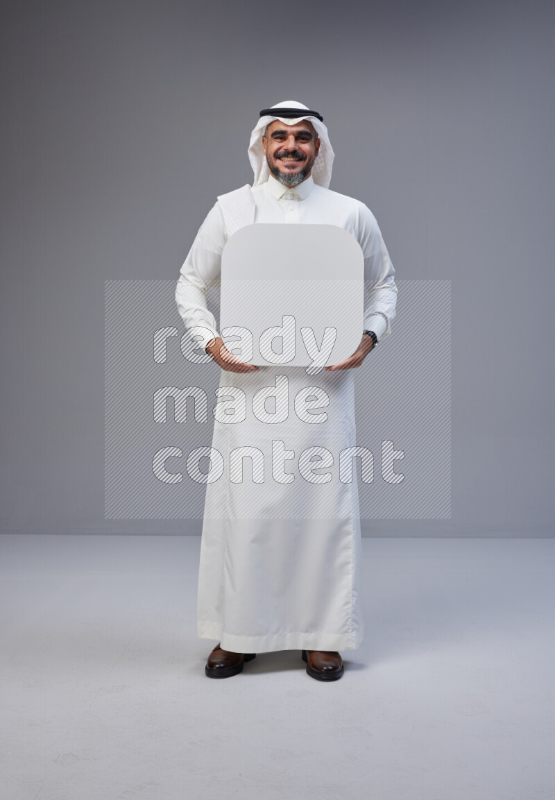 Saudi man Wearing Thob and white Shomag standing holding social media sign on Gray background
