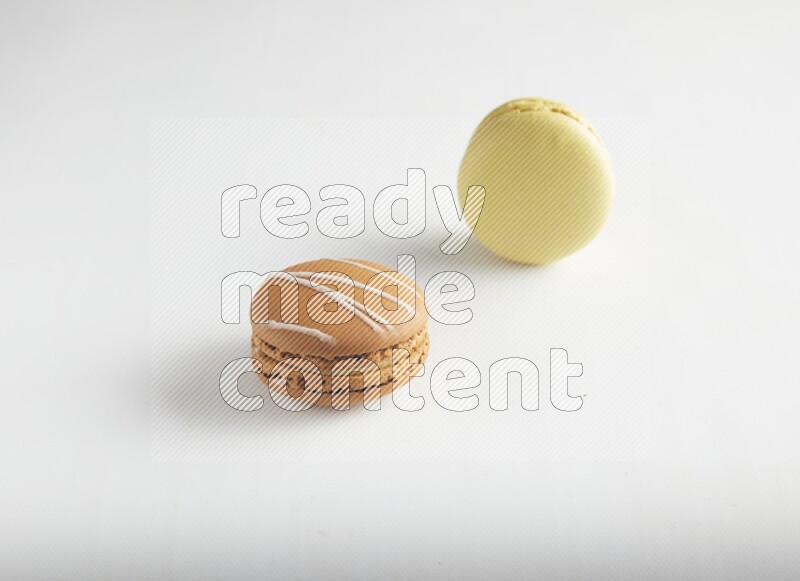 45º Shot of of two assorted Brown Irish Cream, and Yellow Lime macarons on white background