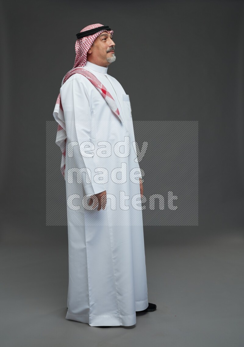 Saudi man with shomag Standing Interacting with the camera on gray background