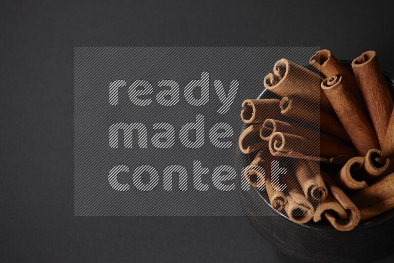 أعواد القرفة في وعاء فخاري أسود علي خلفية سوداء