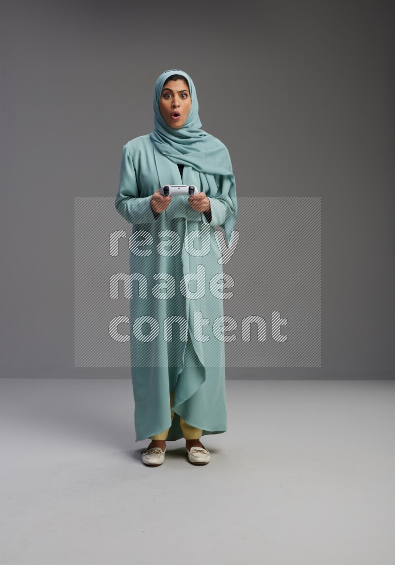 Saudi Woman wearing Abaya standing Playing Games on Gray background