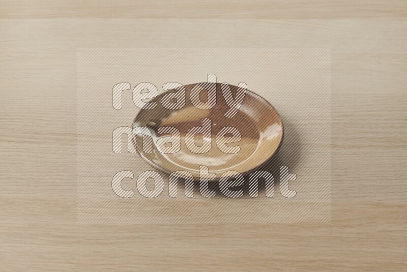 A multicolored pottery plate on light wooden background