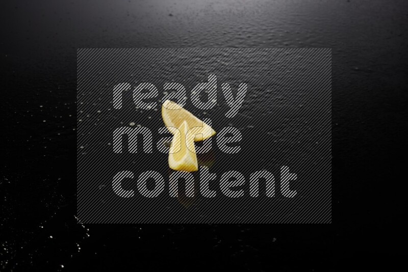 Lemon wedges with water drops, and droplets on black background