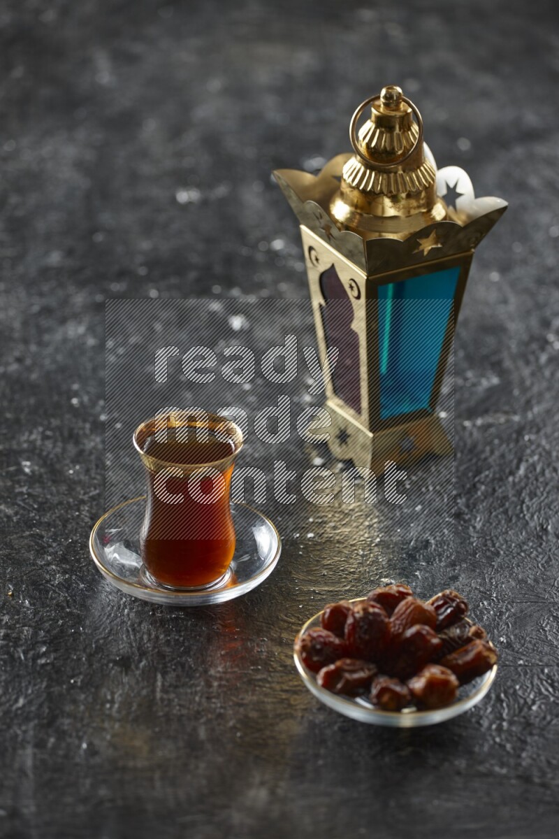 A golden lantern with different drinks, dates, nuts, prayer beads and quran on textured black background