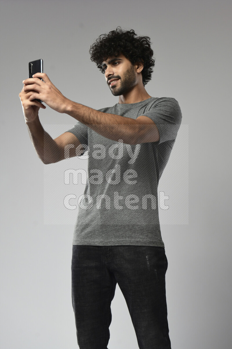 A man wearing casual standing and taking a selfie on white background