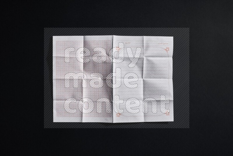 Folded notebook sheet on black background