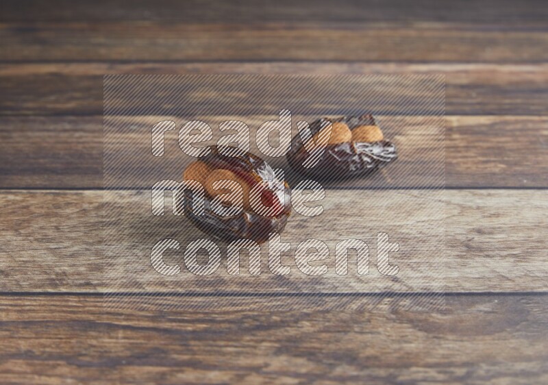two almond stuffed madjoul dates on a wooden background