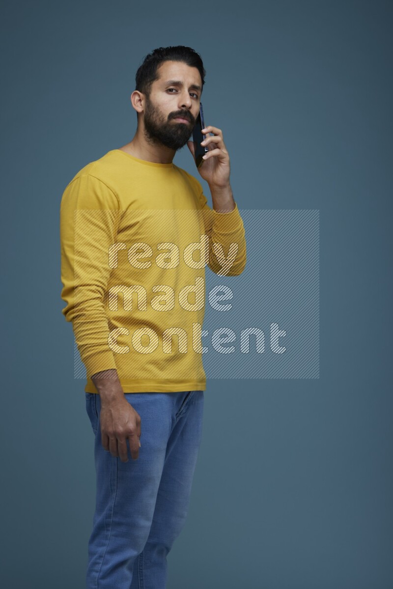 A man having a calling in a blue background wearing a yellow shirt