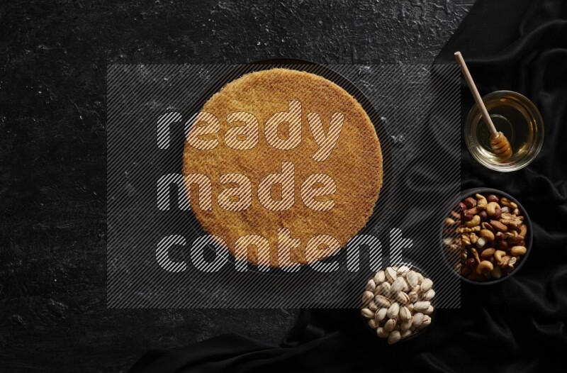 Konafa with nuts and honey in a dark setup