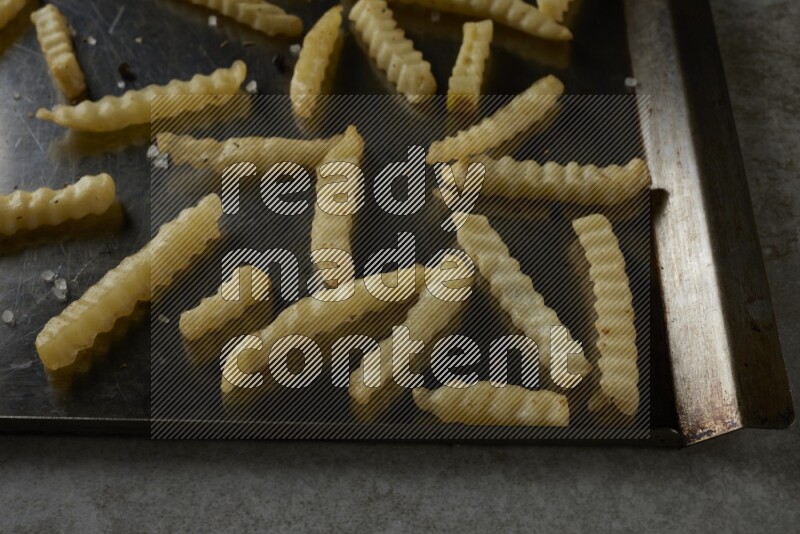 crinkle fries in a black stainless steel rectangle tray on grey textured counter top