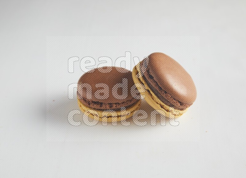 45º Shot of two Yellow and Brown Chai Latte macarons on white background