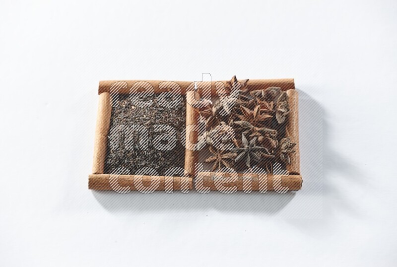 مربعان من أعواد القرفة ممتلئان بالشاي الأسود واليانسون النجمي علي خلفية بيضاء