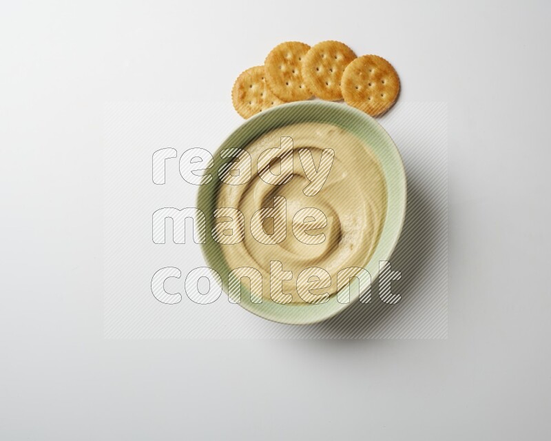 plain Hummus in a green plate on a white background