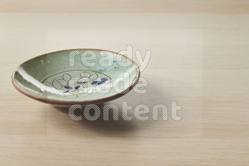 A decorative pottery plate on light wooden background