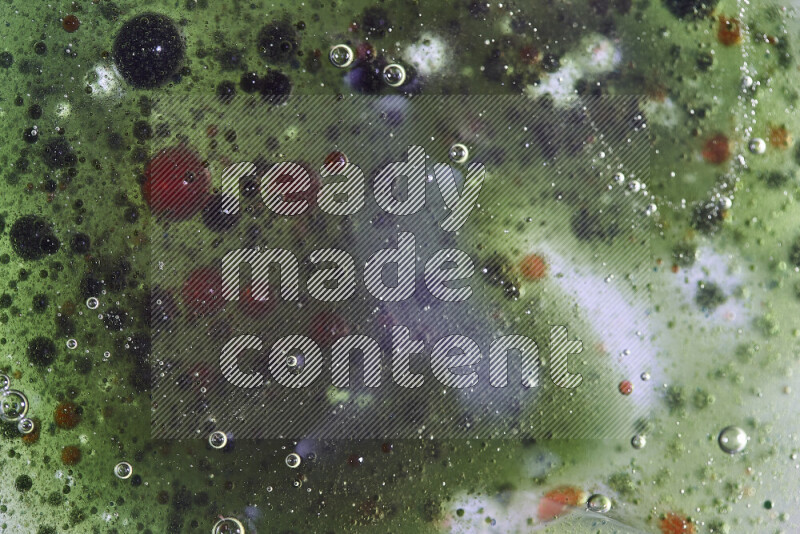 Close-ups of abstract red, green and blue watercolor drops on oil Surface on green background