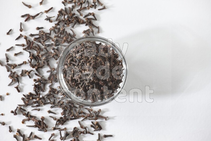 A glass bowl full of cloves on a white flooring
