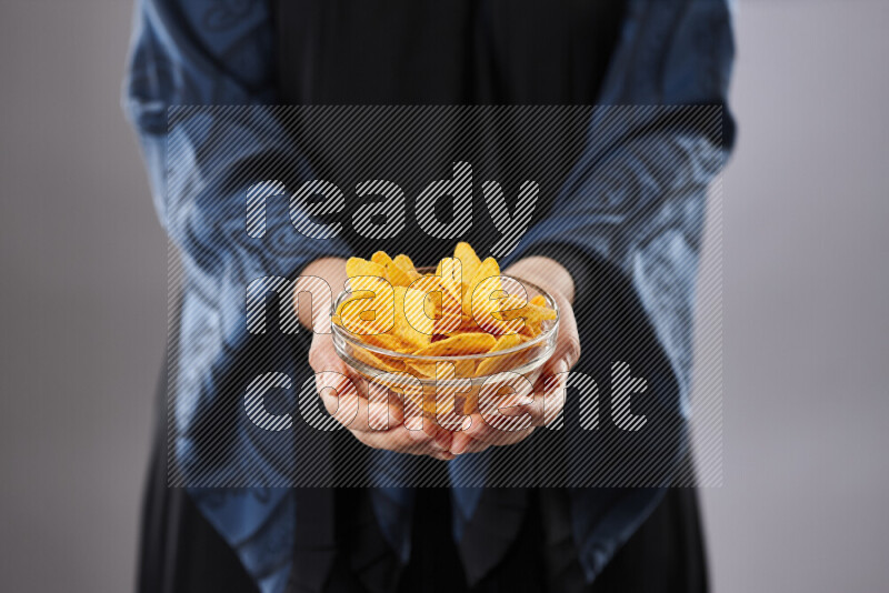 Woman in abaya holding different kinds of snacks in different positions
