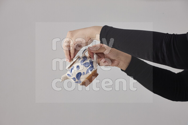 A woman in black abaya holding different pottery essentials in different positions