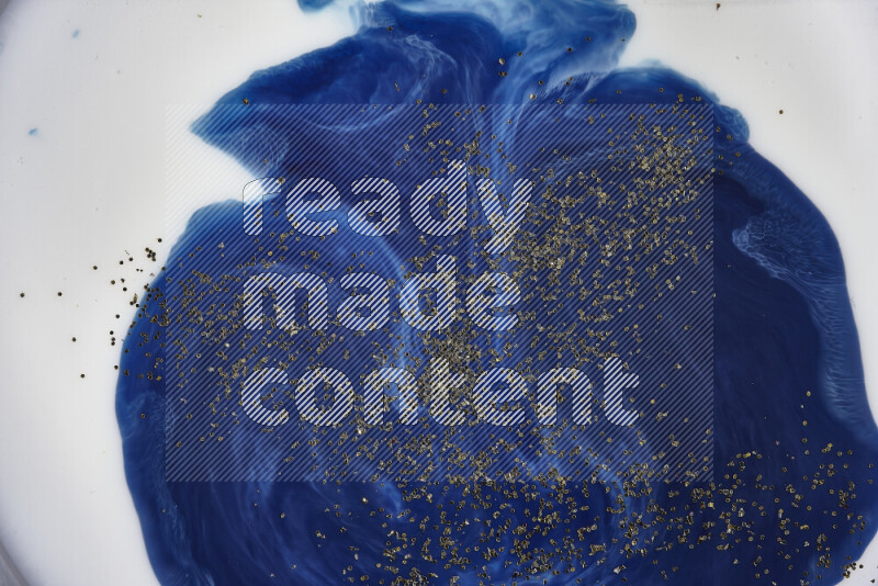 لقطة مقربة لبريق ذهبي متلألئ منتشر على خلفية من اللون الأزرق في حركات دائرية