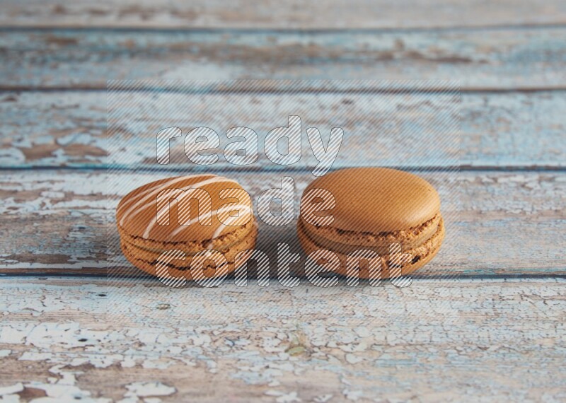 45º Shot of of two assorted Brown Irish Cream, and Brown Maple Taffy macarons  on light blue background