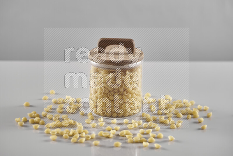 Raw pasta in a glass jar on light grey background