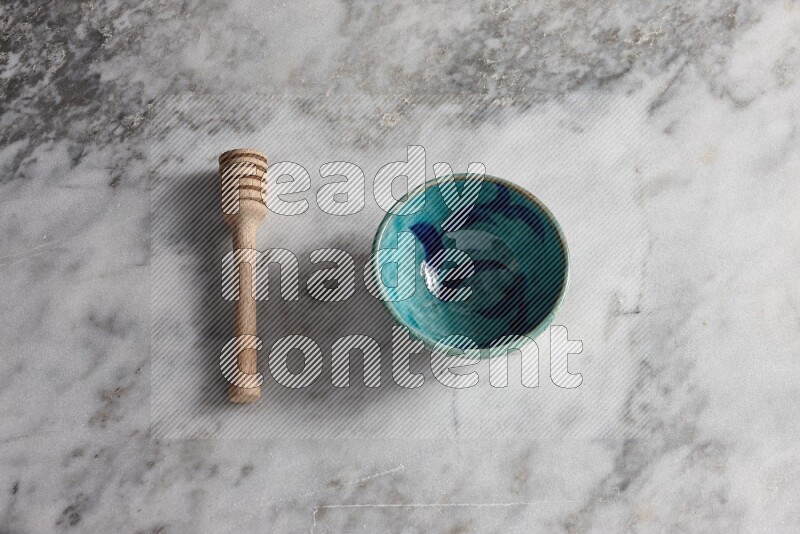 Decorative pottery bowl with wooden honey dipper on the side on grey marble background