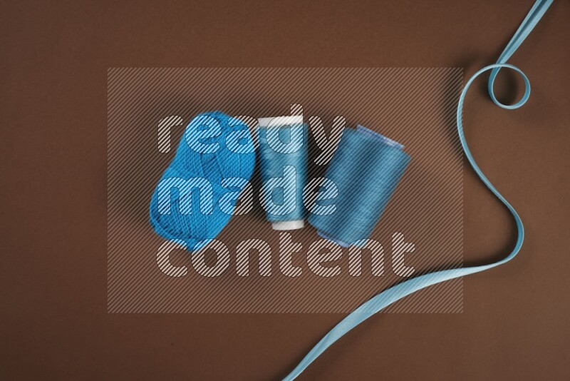 A blue collection of sewing and tailoring tools arranged on a brown background