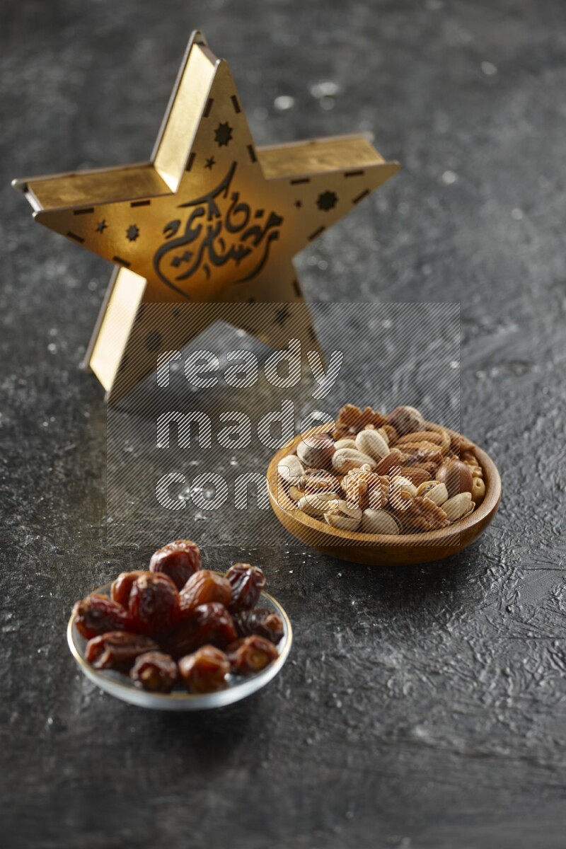 A wooden golden star lantern with different drinks, dates, nuts, prayer beads and quran on textured black background