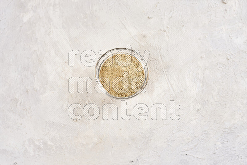A glass bowl full of ground ginger powder on white background