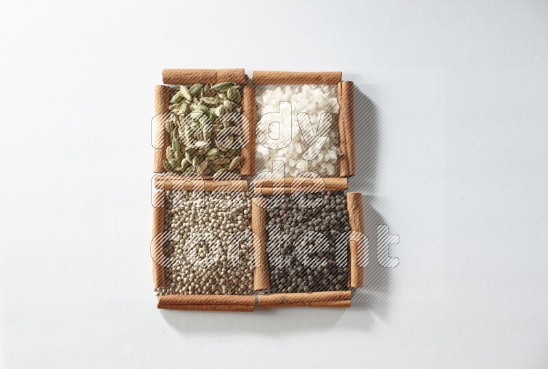 4 squares of cinnamon sticks full of cardamom, salt, white pepper and black pepper on white flooring