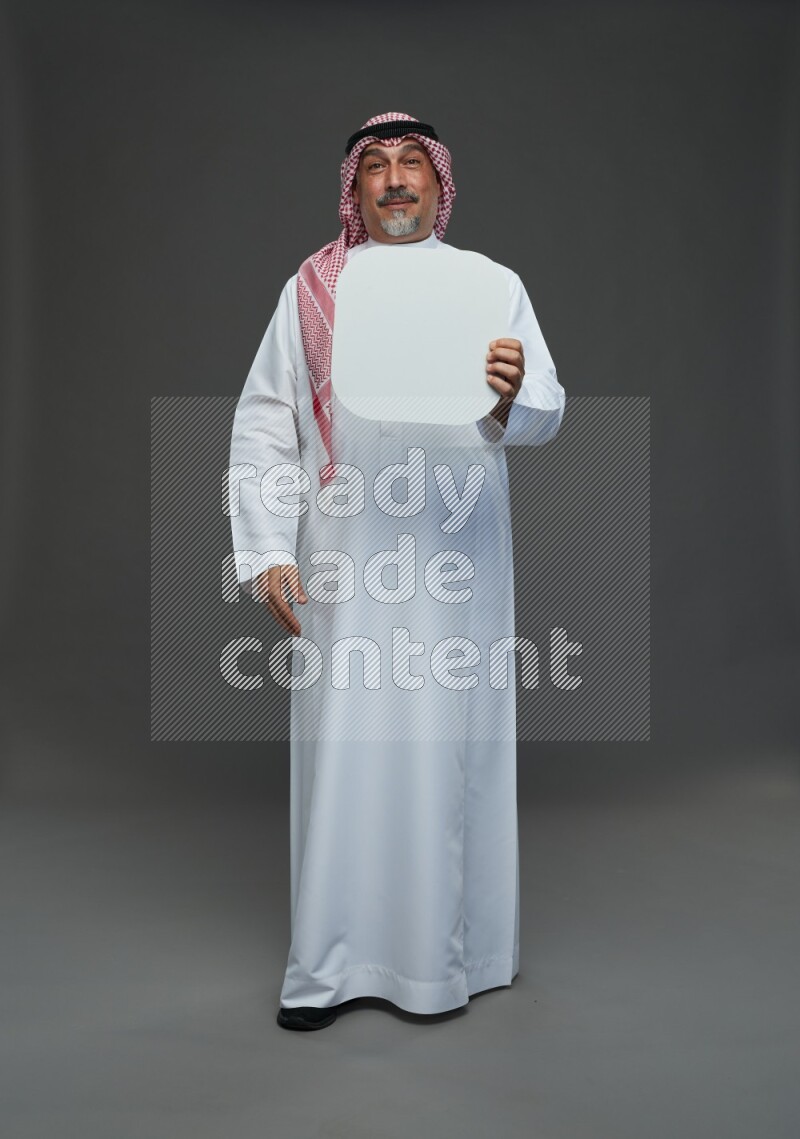 Saudi man with shomag Standing holding social media sing on gray background