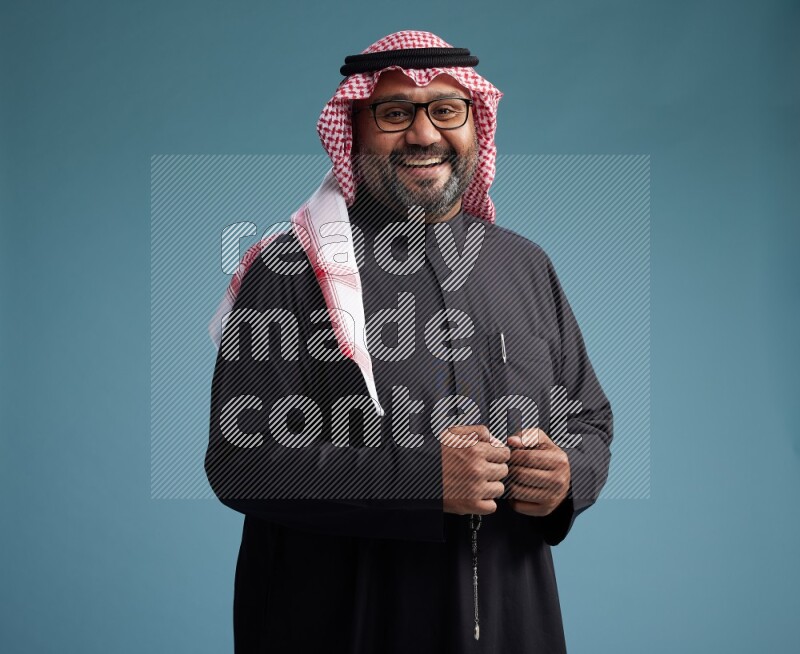 Saudi Man with shimag Standing Interacting with the camera on blue background