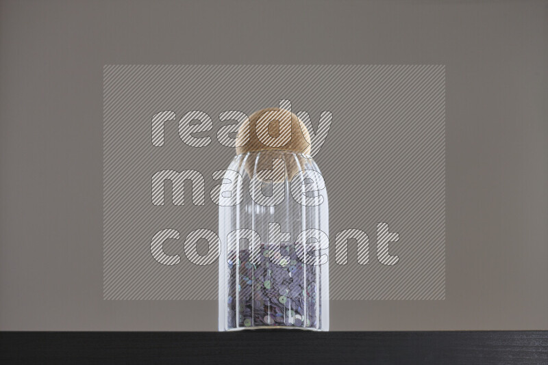 Sequins in a glass jar on black background