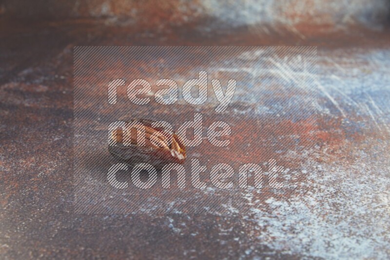 one pecan stuffed madjoul date on a rustic reddish background