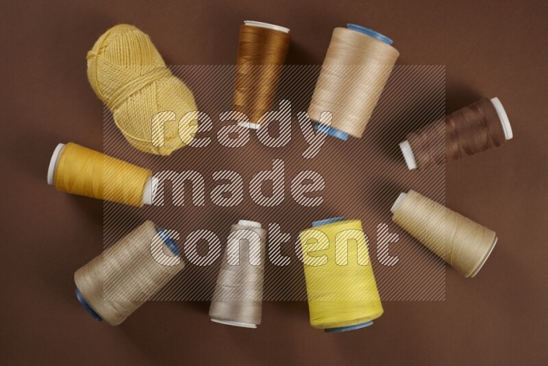 A yellow collection of sewing and tailoring tools arranged on a brown background
