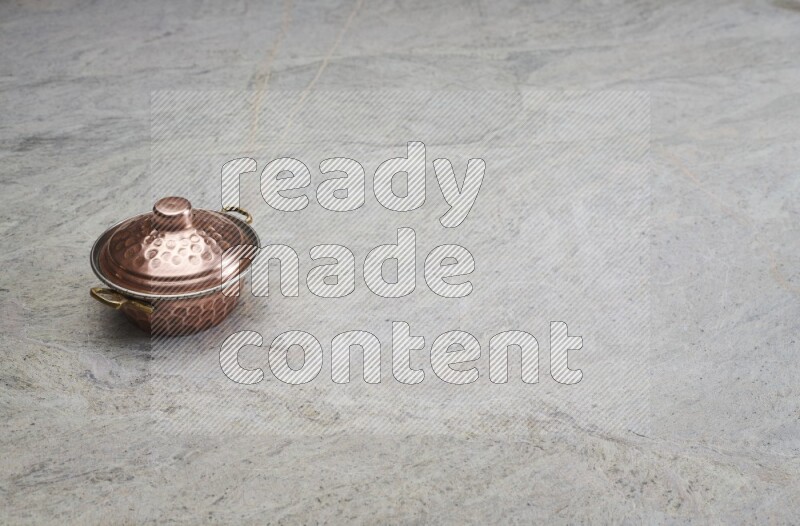 A small copper pot on grey marble background