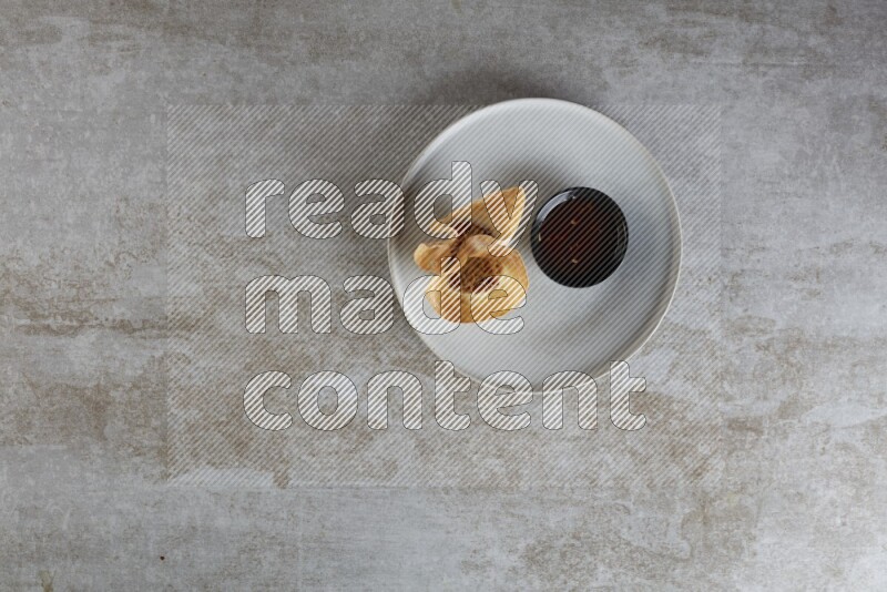 wonton cups with soy sauce ramkin on grey ceramic plate on grey textured counter top