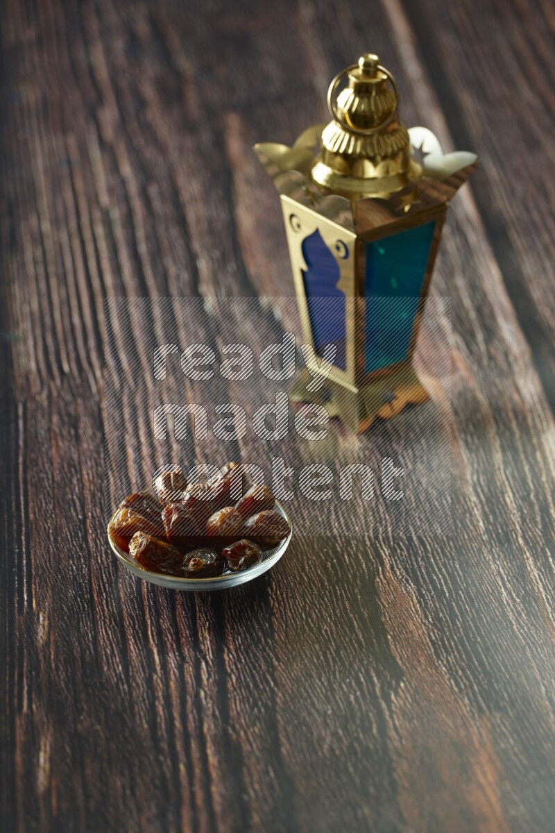 A golden lantern with different drinks, dates, nuts, prayer beads and quran on brown wooden background