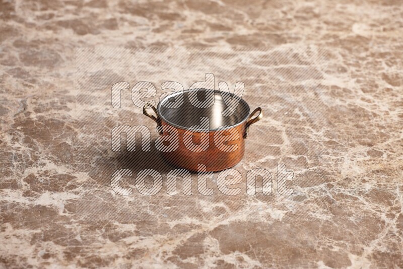 A small copper pot on beige marble background