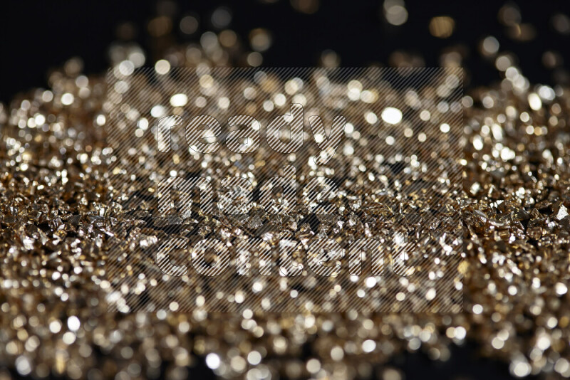 Gold shimmering fragments of glass scattered on a black background