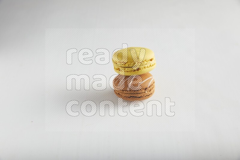 45º Shot of of two assorted Brown Irish Cream, and Yellow Lemon macarons on white background