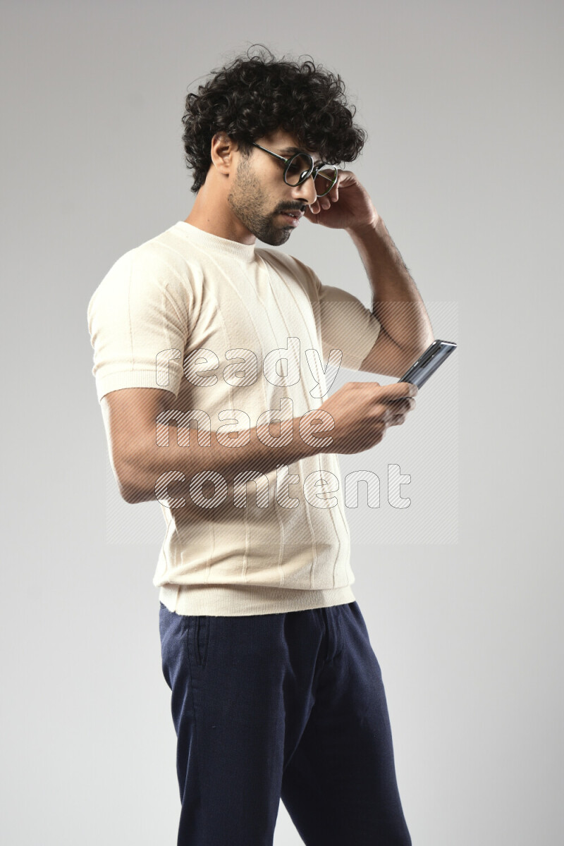 A man wearing casual standing and browsing on the phone on white background