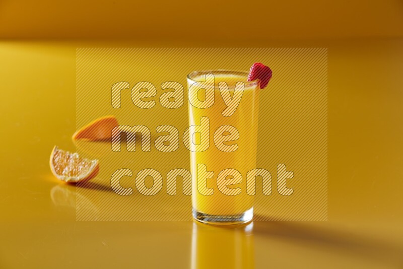 glass of orange juice with berry on yellow background